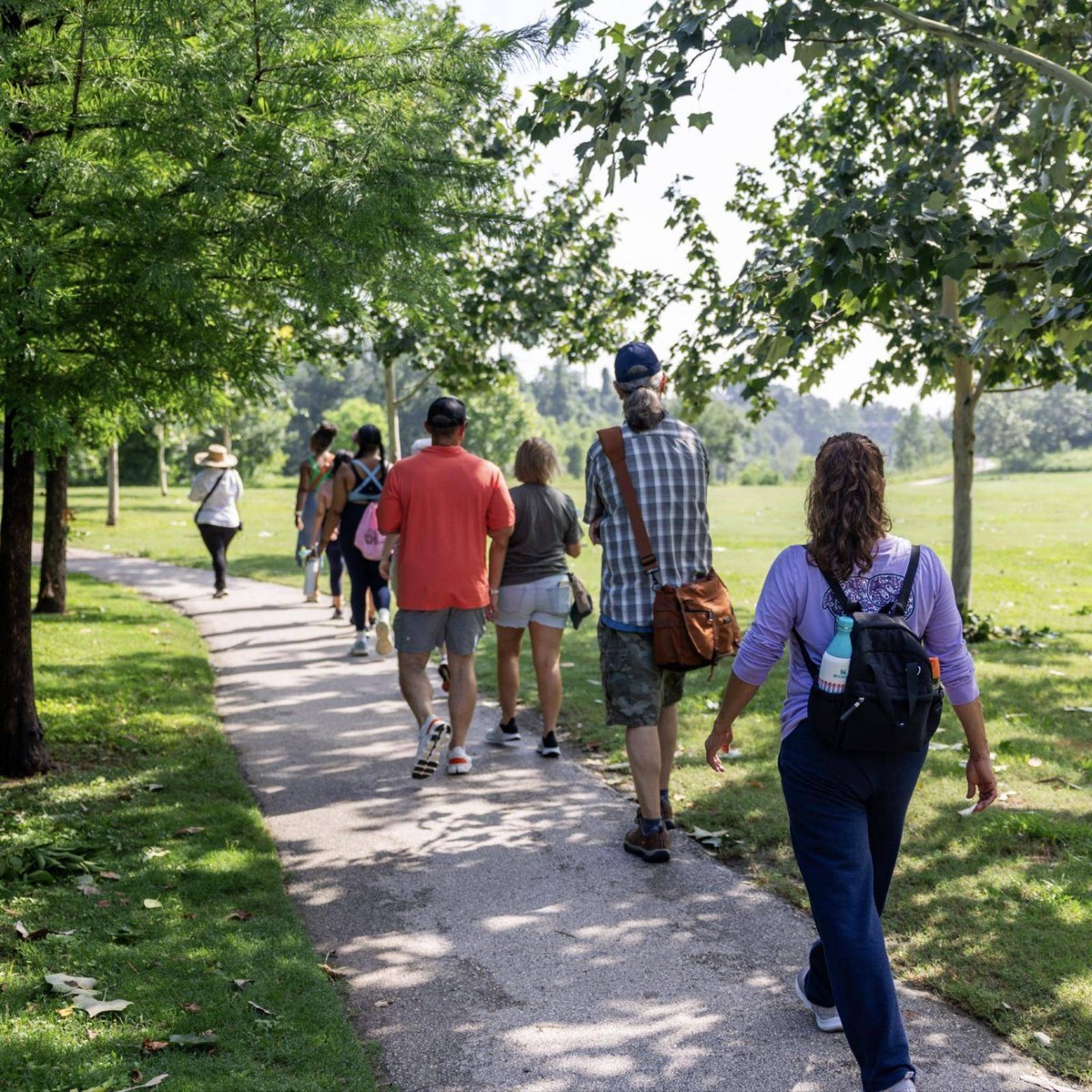 A Buffalo Bayou Partnership nature walk group on a shaded trail in Buffalo Bayou Park